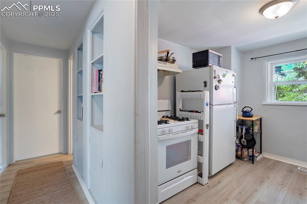 Image 9 of 28: Kitchen featuring white appliances, light wood finished floors, and under c