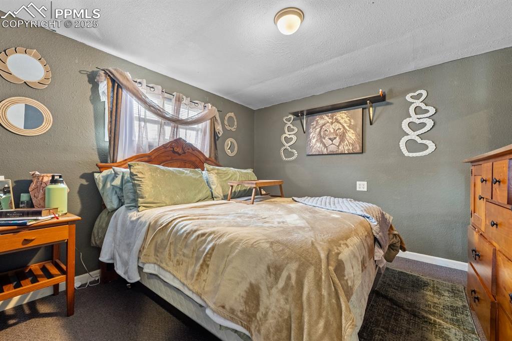 Image 10 of 24: Bedroom featuring a textured wall, dark carpet, and a textured ceiling