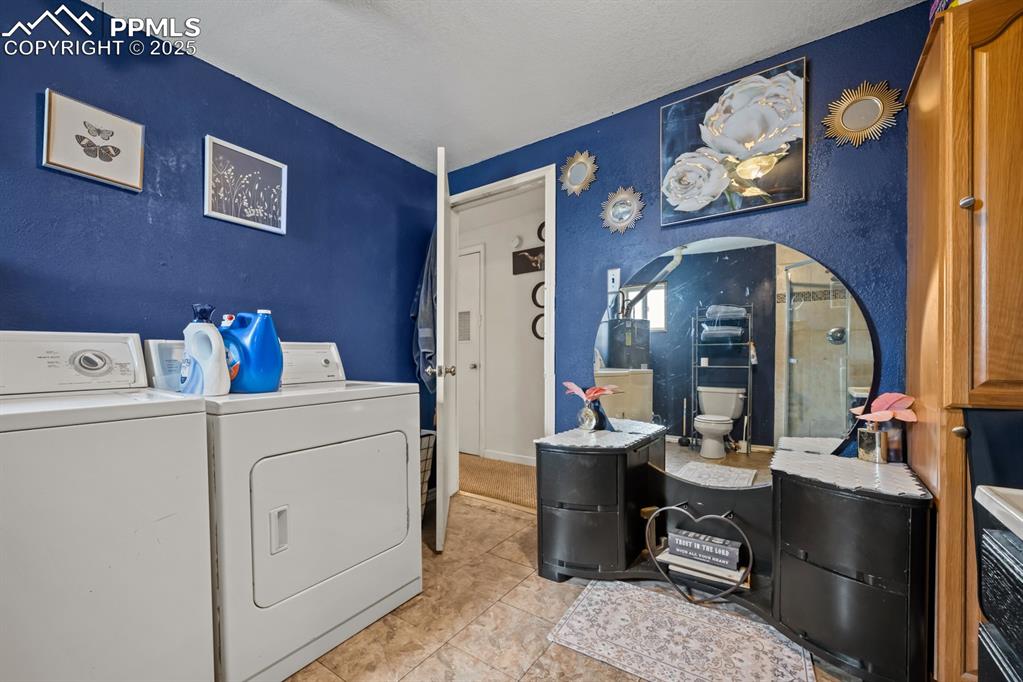 Image 15 of 24: Washroom with washer and clothes dryer, light tile patterned floors, and a