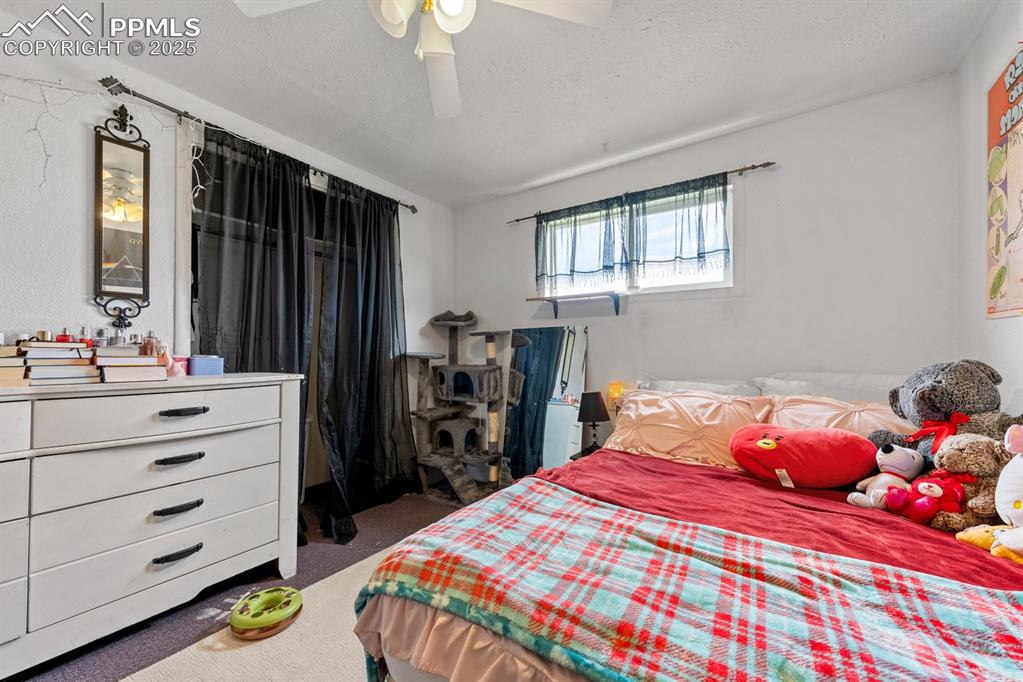 Image 16 of 24: Bedroom with dark carpet, a textured ceiling, and ceiling fan
