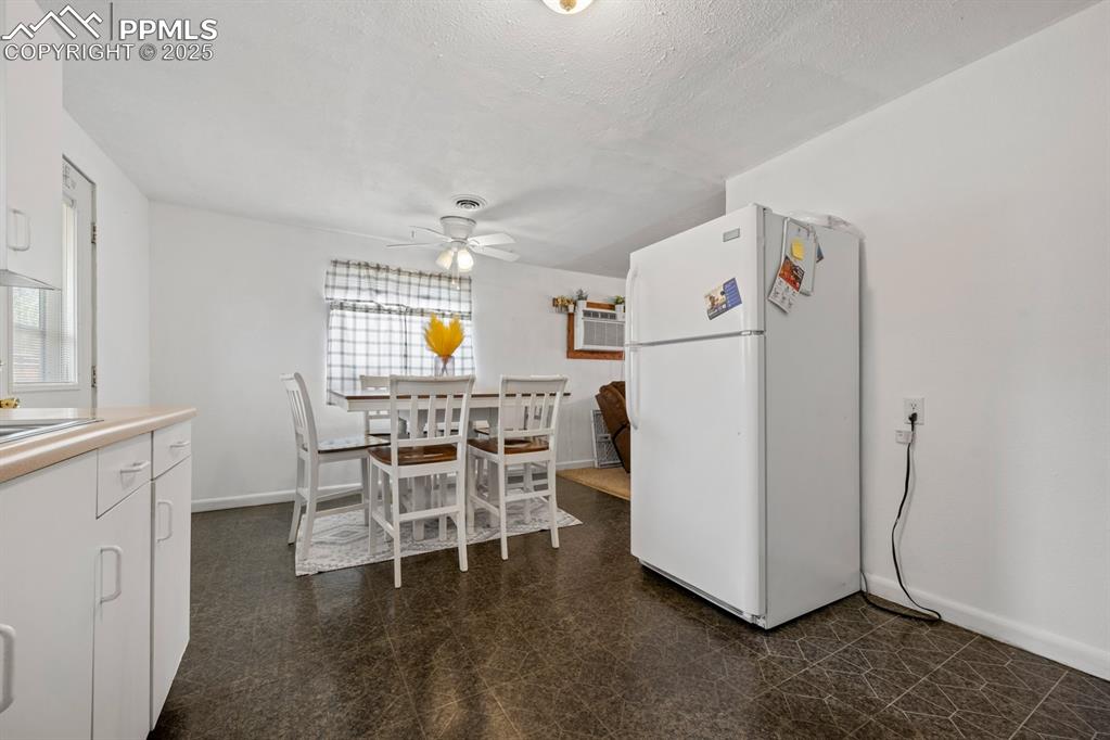 Image 9 of 24: Dining space featuring dark flooring, a wall mounted AC, and ceiling fan
