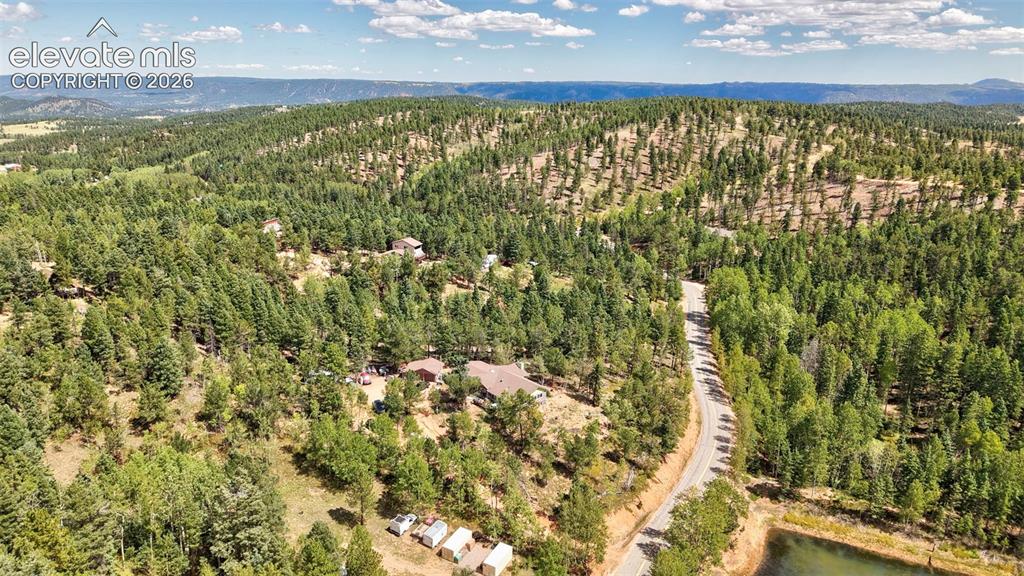 Image 10 of 21: Wooded terrain with a paved road, distant mountain ranges.
