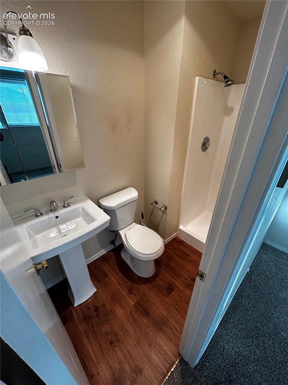 Image 5 of 12: Compact bathroom featuring wood-finish flooring, a white pedestal sink, a t