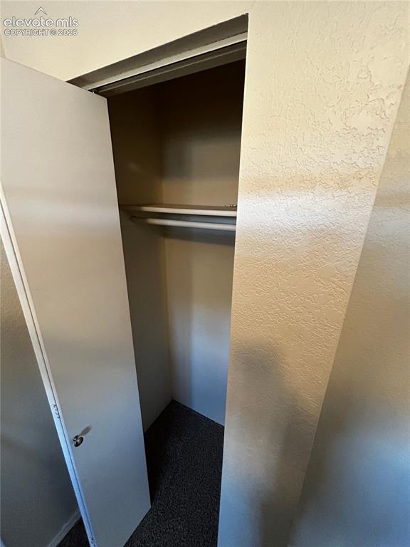 Image 8 of 12: Recessed closet featuring a single hanging rod, textured beige walls, and d