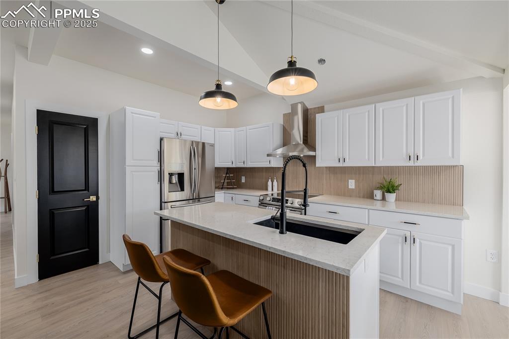 Image 10 of 39: Kitchen with hanging light fixtures, decorative backsplash, white cabinetry