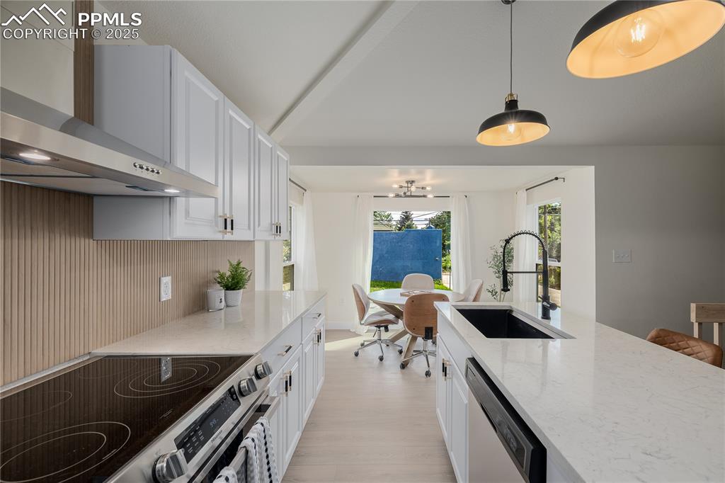 Image 11 of 39: Kitchen featuring appliances with stainless steel finishes, light stone cou