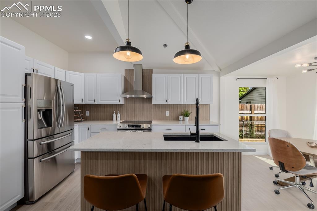 Image 12 of 39: Kitchen with decorative backsplash, light stone counters, appliances with s