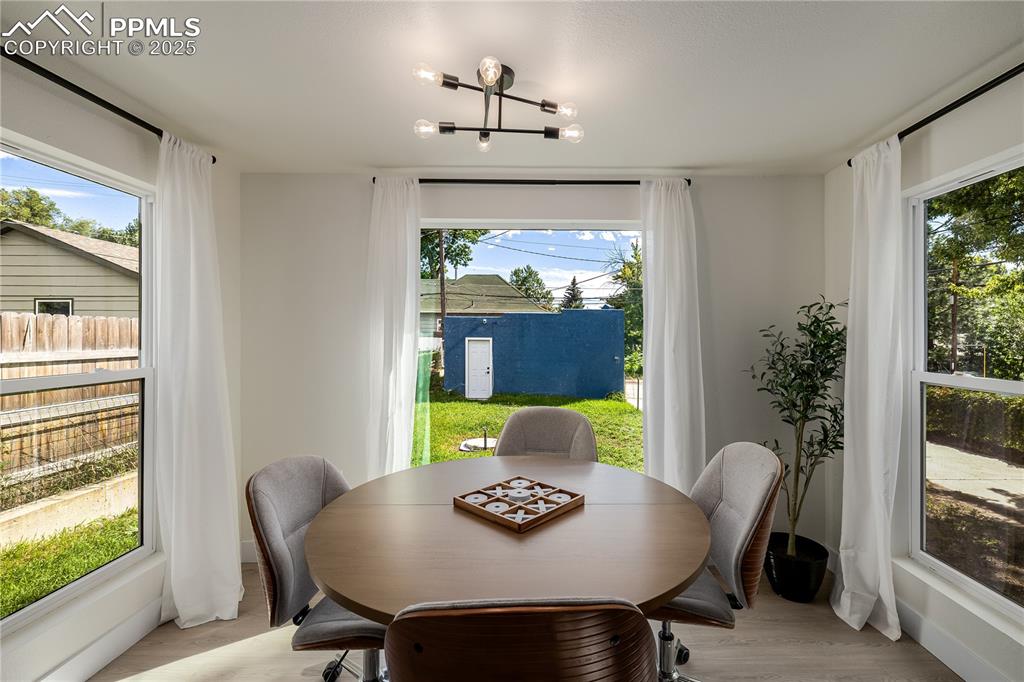 Image 16 of 39: Dining space with wood finished floors, plenty of natural light, and a chan