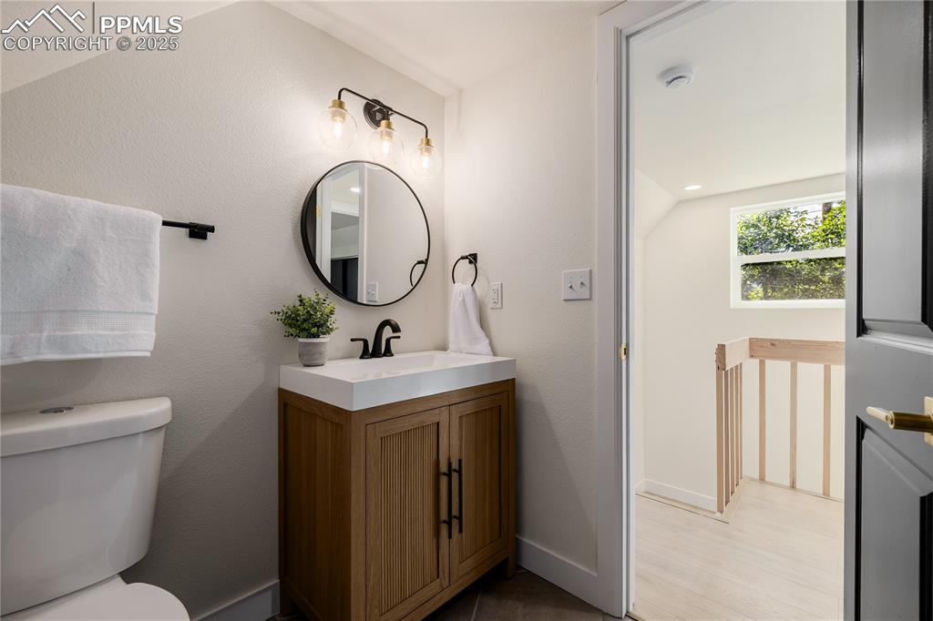 Image 28 of 39: Bathroom featuring vanity, a textured wall, and light wood-style floors