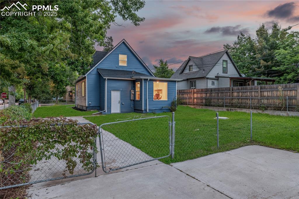 Image 34 of 39: Back of house at dusk featuring a fenced front yard and a gate