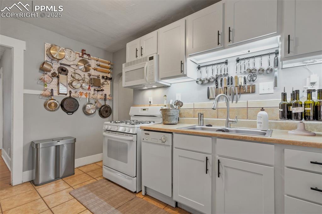 Image 11 of 49: Kitchen featuring white appliances, light countertops, white cabinets, and 