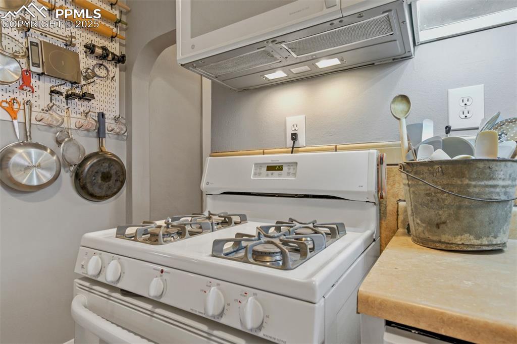 Image 14 of 49: Kitchen featuring extractor fan, white range with gas stovetop, and wooden 
