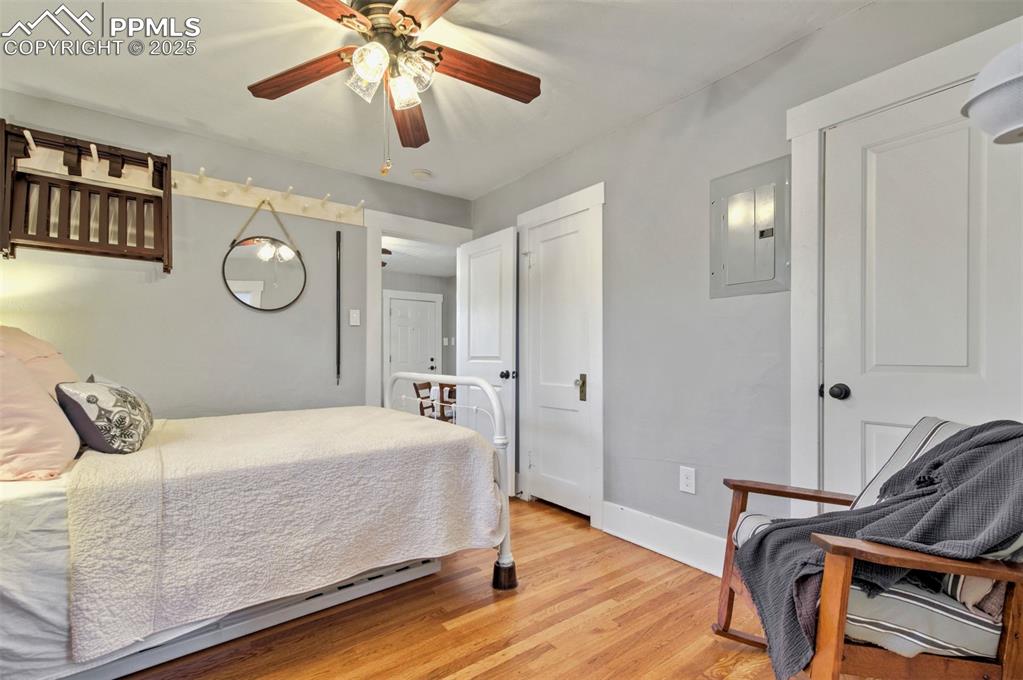 Image 20 of 49: Bedroom with electric panel, light wood-style flooring, and a ceiling fan