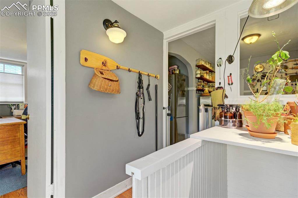 Image 27 of 49: Hallway featuring light wood-style floors, arched walkways, and a desk