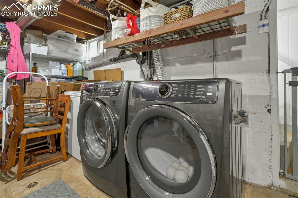 Image 32 of 49: Laundry room featuring unfinished concrete floors and washing machine and d