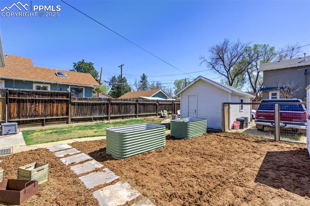 Image 41 of 49: Fenced backyard featuring an outbuilding and a vegetable garden