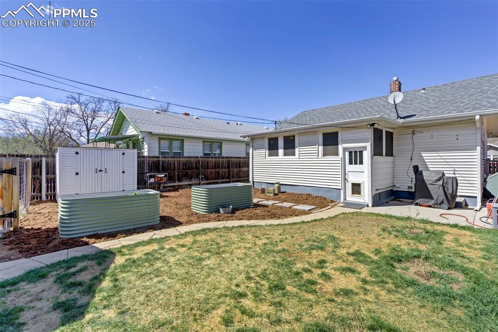 Image 44 of 49: Rear view of house featuring a fenced backyard, a shingled roof, and a chim