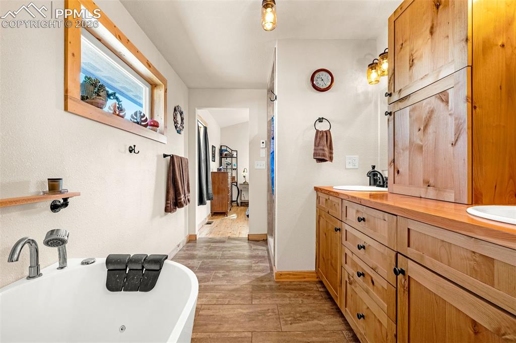 Image 15 of 50: Bathroom with a freestanding tub, double vanity, and light wood finished fl