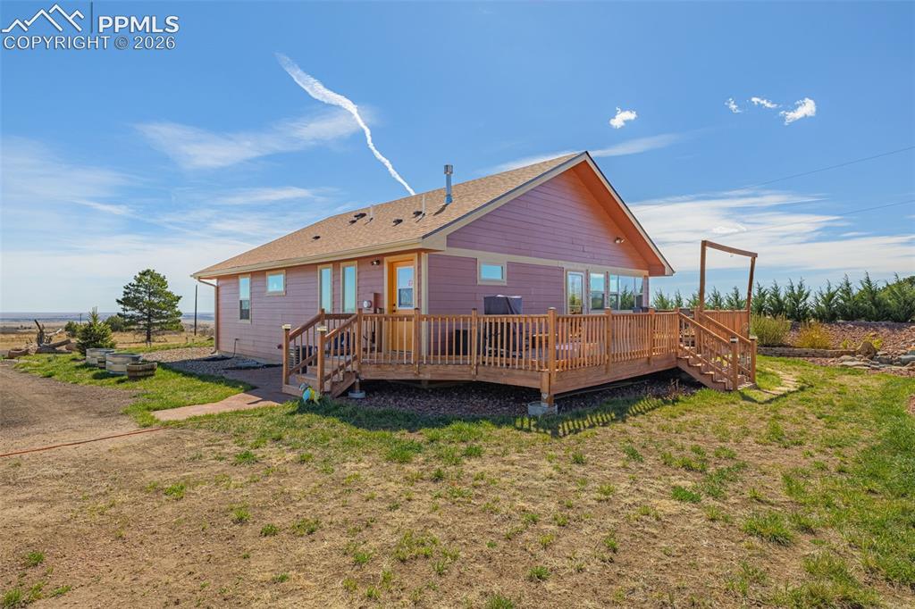 Image 28 of 50: Back of property with a wooden deck and a yard