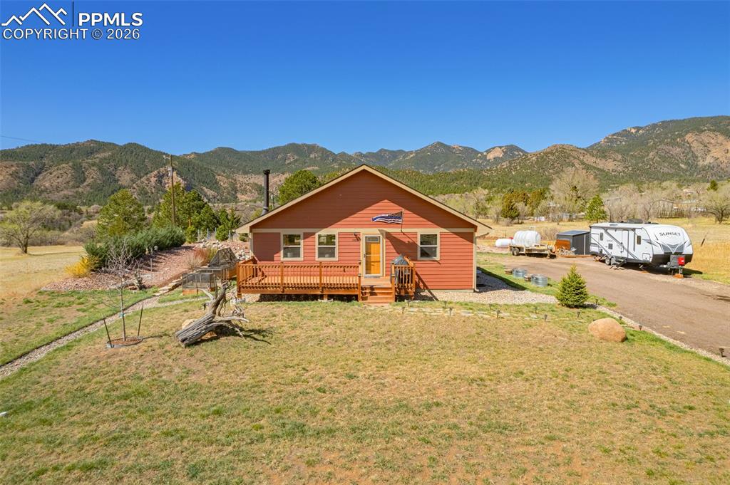 Image 39 of 49: View of front of house featuring a deck with mountain view and a front lawn