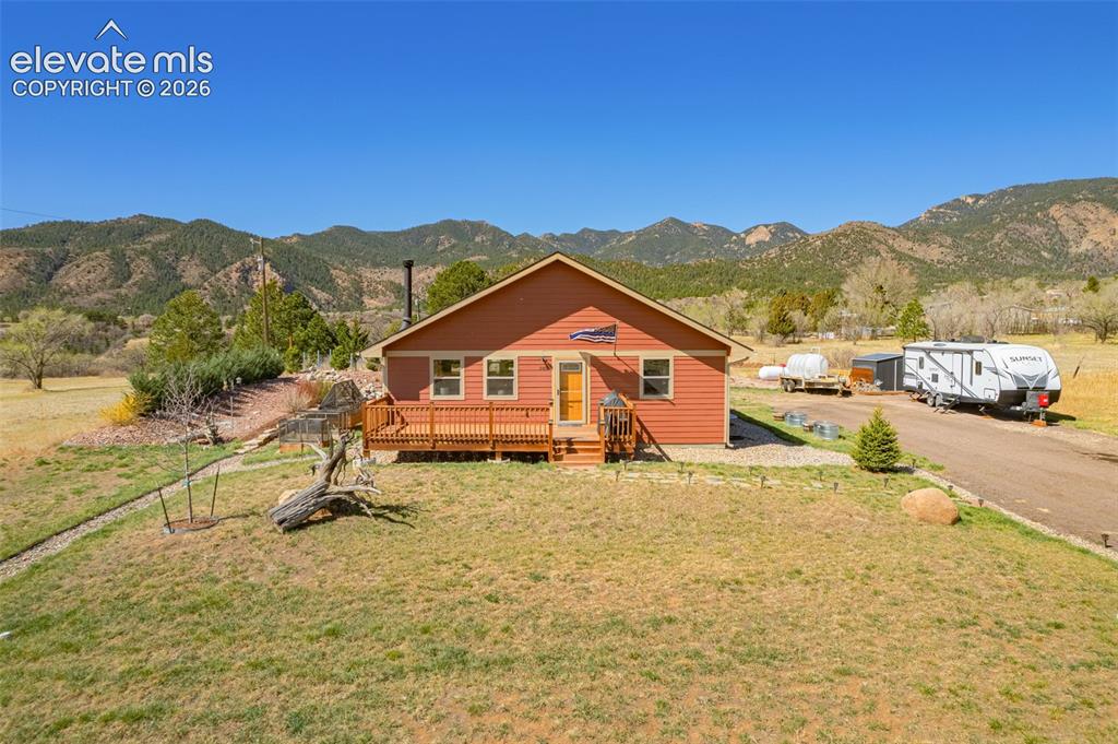 Image 40 of 50: View of front of house featuring a deck with mountain view and a front lawn
