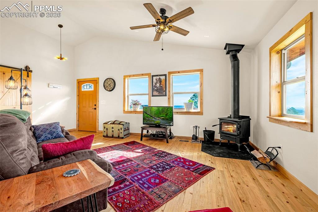 Image 5 of 49: Living area featuring a wood stove, light wood finished floors, lofted ceil