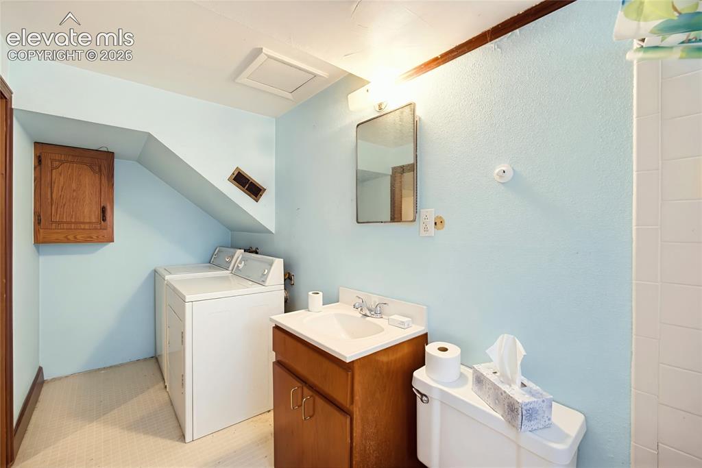 Image 20 of 45: Built-in laundry appliances, wood-finish vanity with an integrated sink, wa