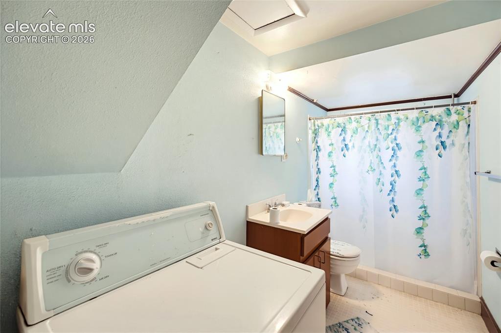 Image 21 of 45: Compact bathroom with a built-in vanity, white sink, and tiled flooring