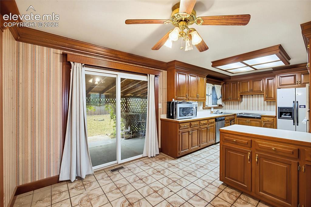 Image 27 of 45: Kitchen featuring wood cabinetry, a center island, tile flooring, and a cei