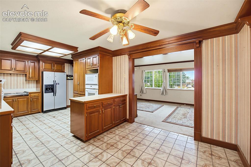 Image 28 of 45: Kitchen featuring wood cabinetry, integrated oven and microwave, and tile f