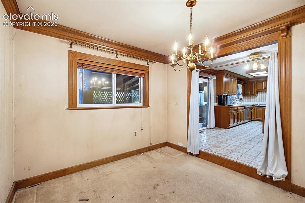 Image 31 of 45: Wood-trimmed window, ornate crown molding, and a brass chandelier, with a s