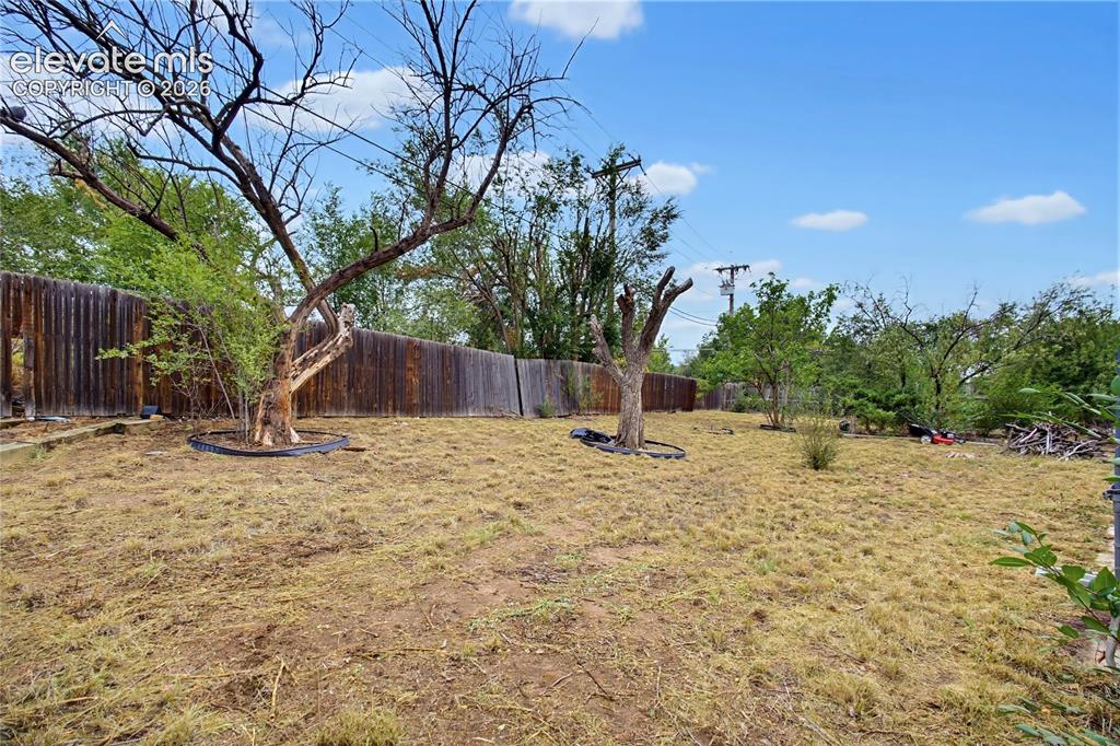 Image 7 of 45: Expansive backyard with a full perimeter wood fence, mature trees, and an o