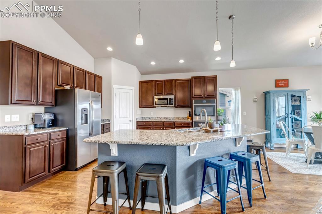 Image 22 of 50: Kitchen featuring stainless steel appliances, a sink, a spacious island, li