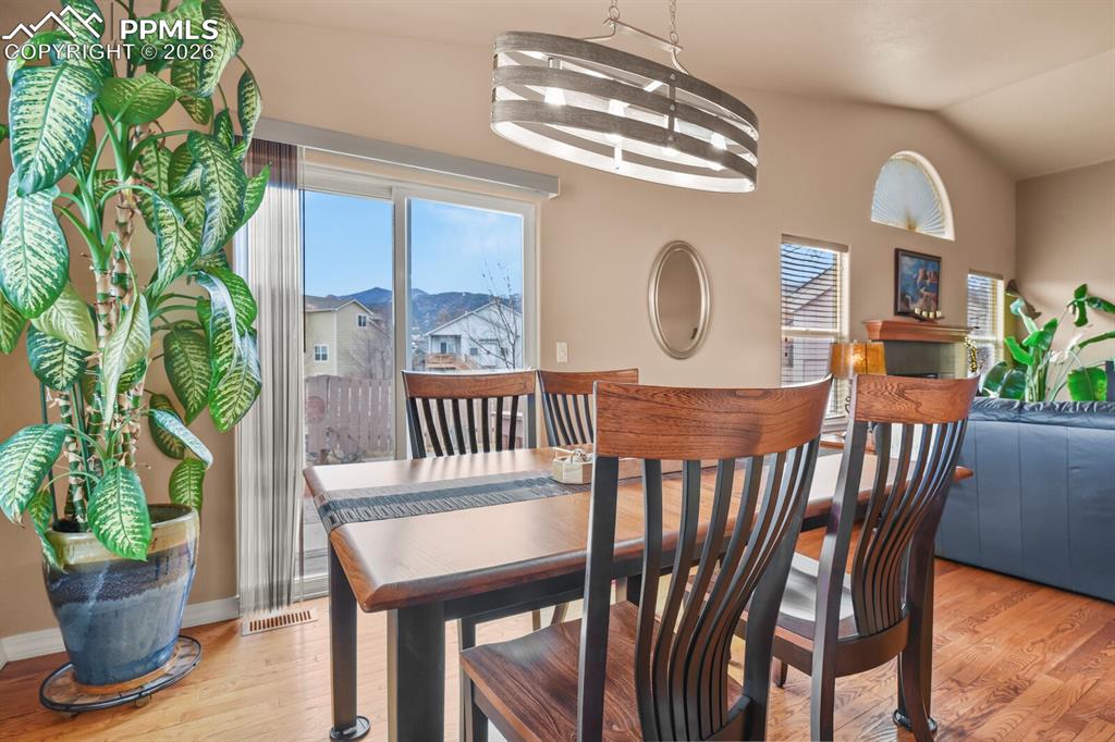 Image 12 of 42: Dining area featuring hardwood floors, chandelier and slider to the outside
