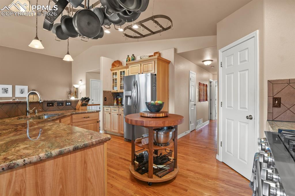 Image 14 of 42: Kitchen with dark stone counters, glass fronted cabinets, stainless steel a