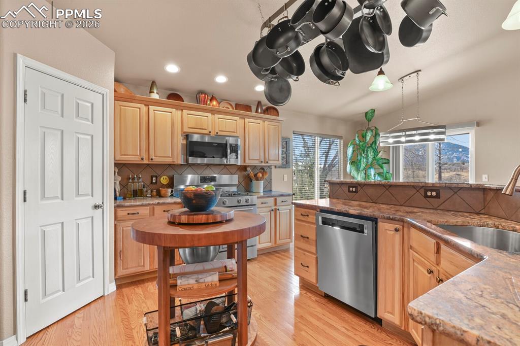 Image 15 of 42: Kitchen with stainless steel appliances, dark stone counters, and light woo