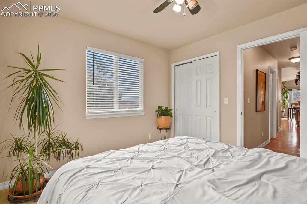 Image 26 of 42: Third bedroom on the main level,  featuring a ceiling fan and a closet