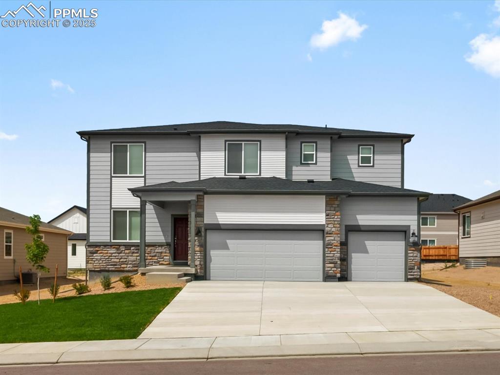 Caption: Prairie-style house featuring stone siding, an attached garage, driveway, and a front yard