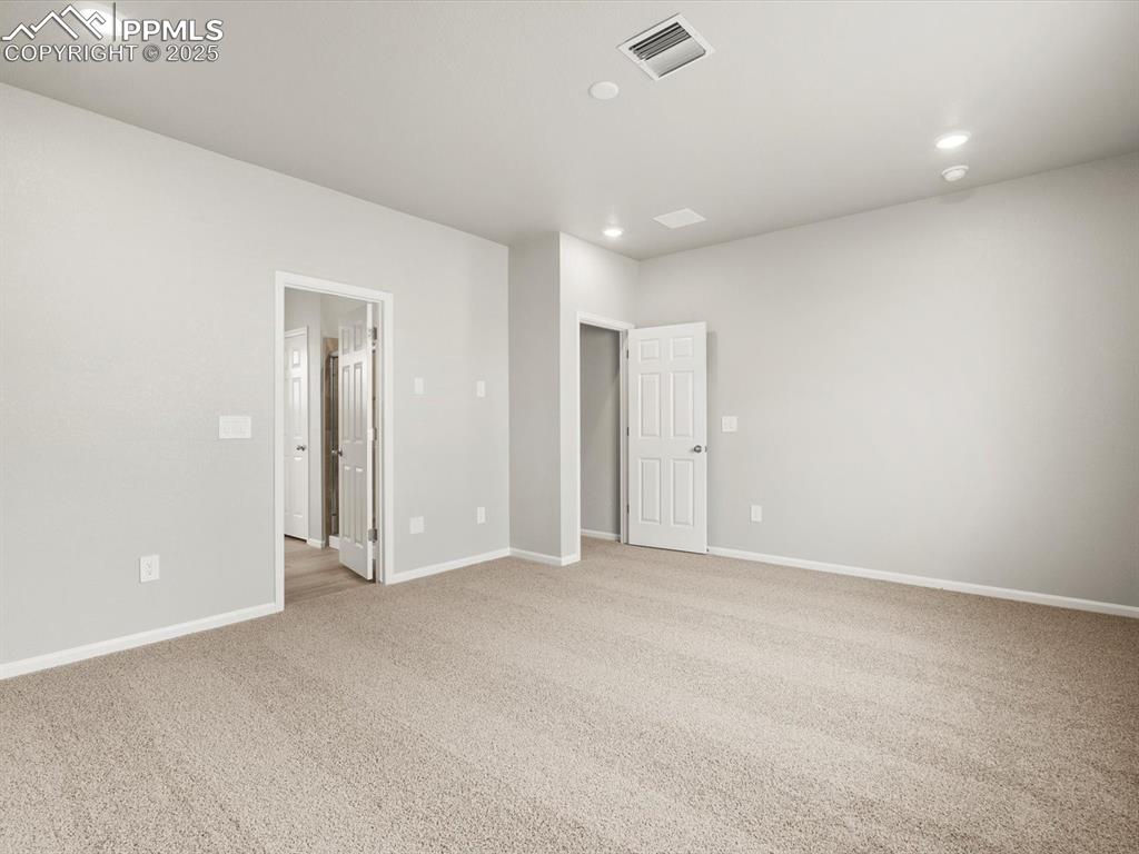 Image 11 of 26: Empty room with light colored carpet and recessed lighting
