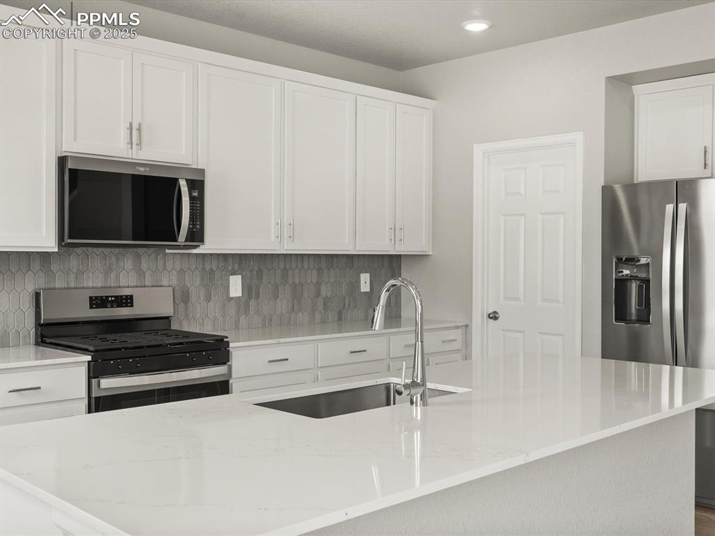 Image 2 of 26: Kitchen featuring appliances with stainless steel finishes, white cabinetry