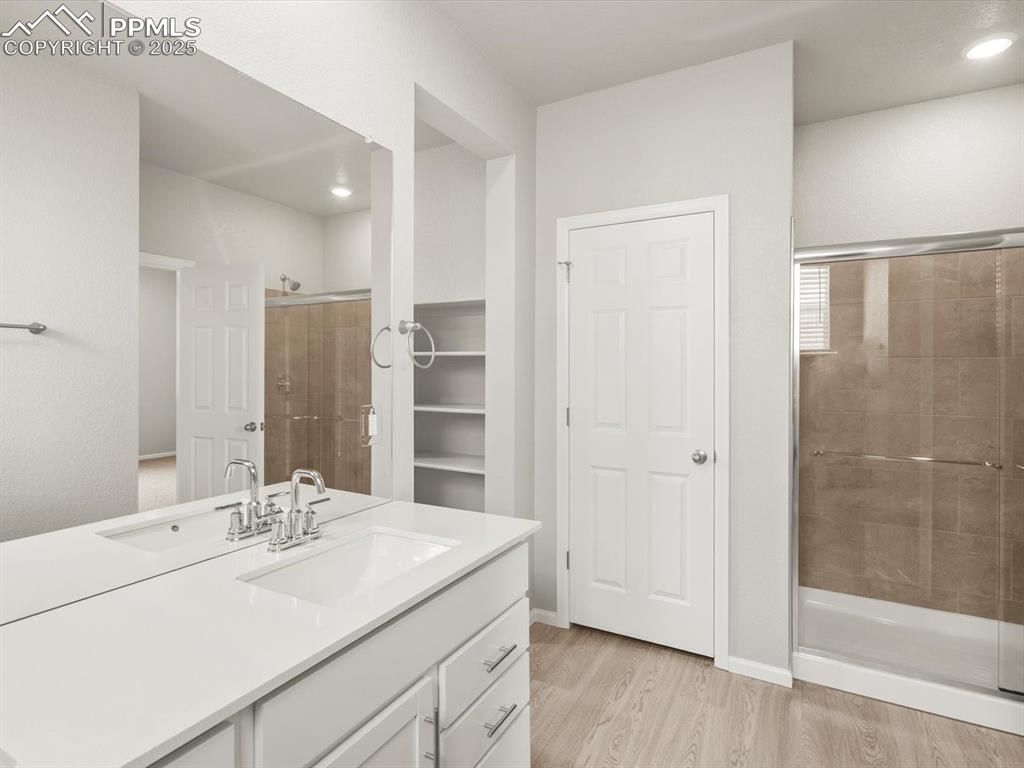 Image 23 of 26: Bathroom featuring vanity, a shower stall, light wood-style flooring, reces