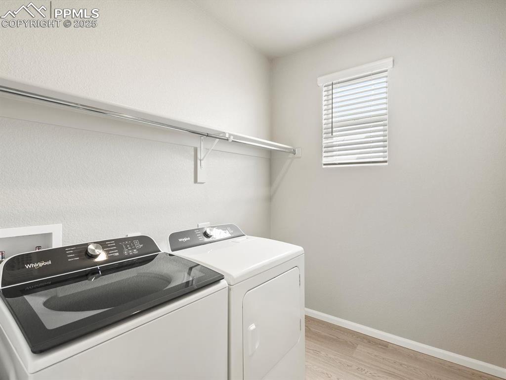 Image 25 of 26: Washroom featuring light wood-style floors and washing machine and dryer