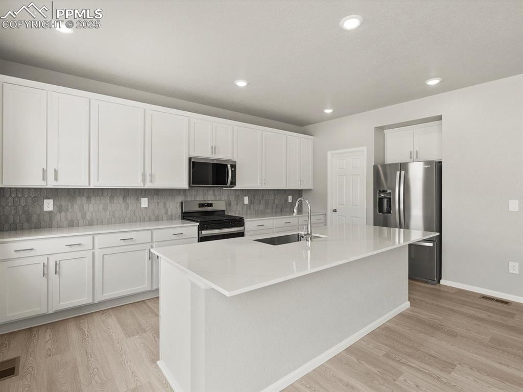 Image 3 of 26: Kitchen featuring backsplash, appliances with stainless steel finishes, whi
