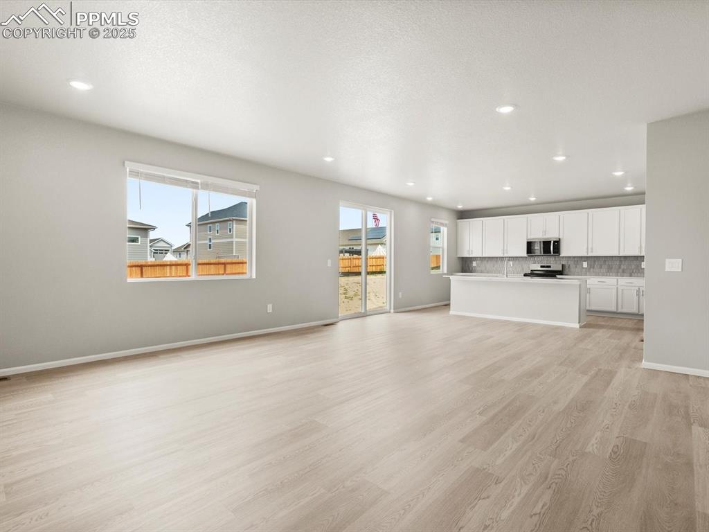 Image 5 of 26: Unfurnished living room with light wood finished floors and recessed lighti