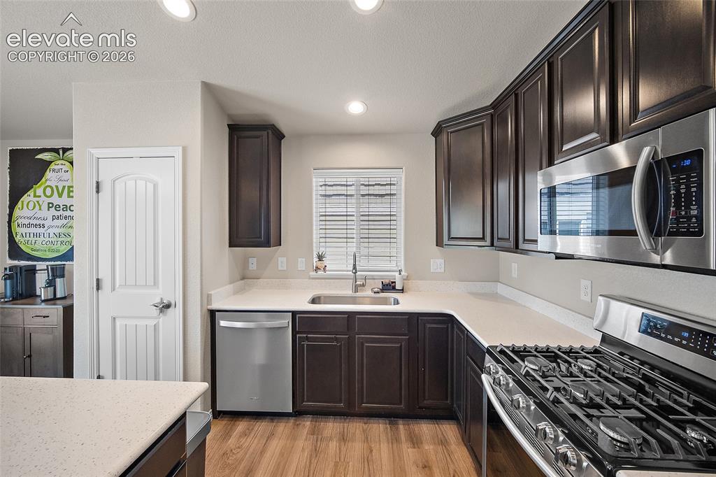 Image 11 of 50: Modern kitchen featuring dark wood cabinetry, light-toned countertops, and