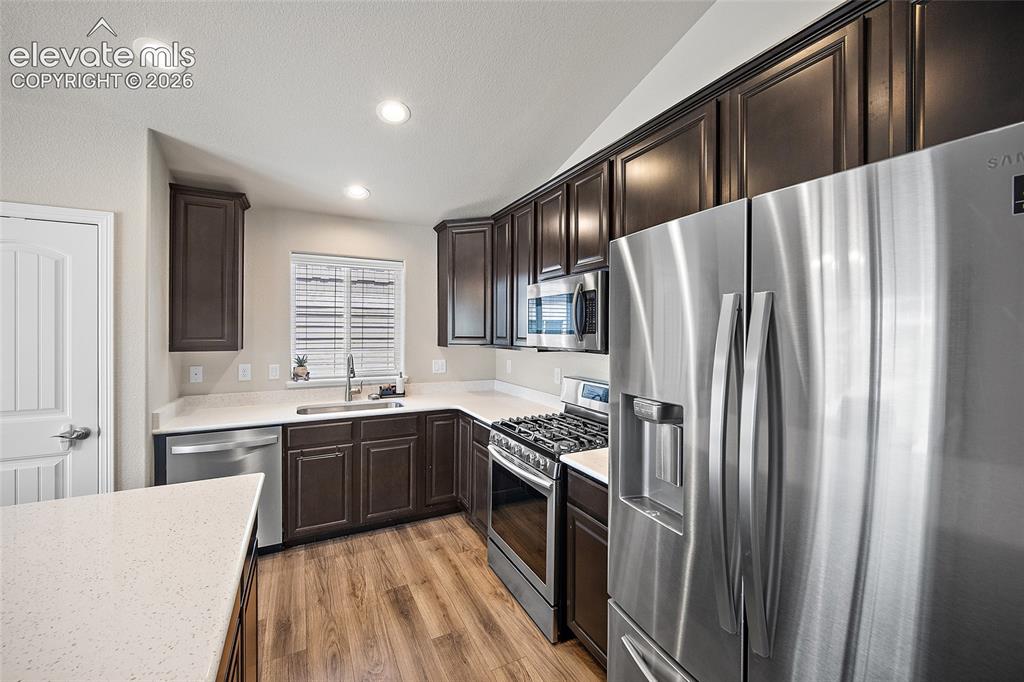 Image 11 of 49: Well-appointed kitchen featuring dark wood cabinetry, stainless steel appli