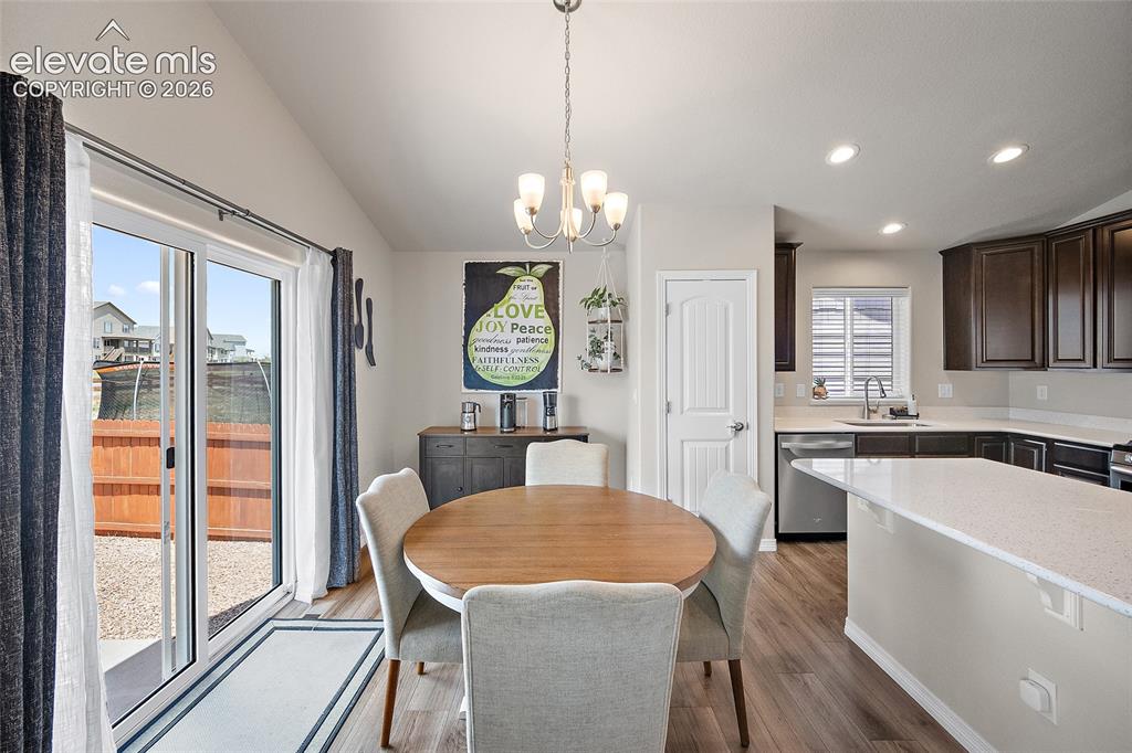 Image 13 of 49: Open-concept kitchen and dining area featuring wood-finish flooring, a vaul