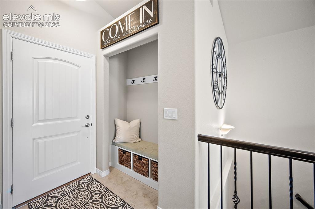 Image 14 of 50: Entryway featuring a built-in bench with storage, multiple coat hooks, and