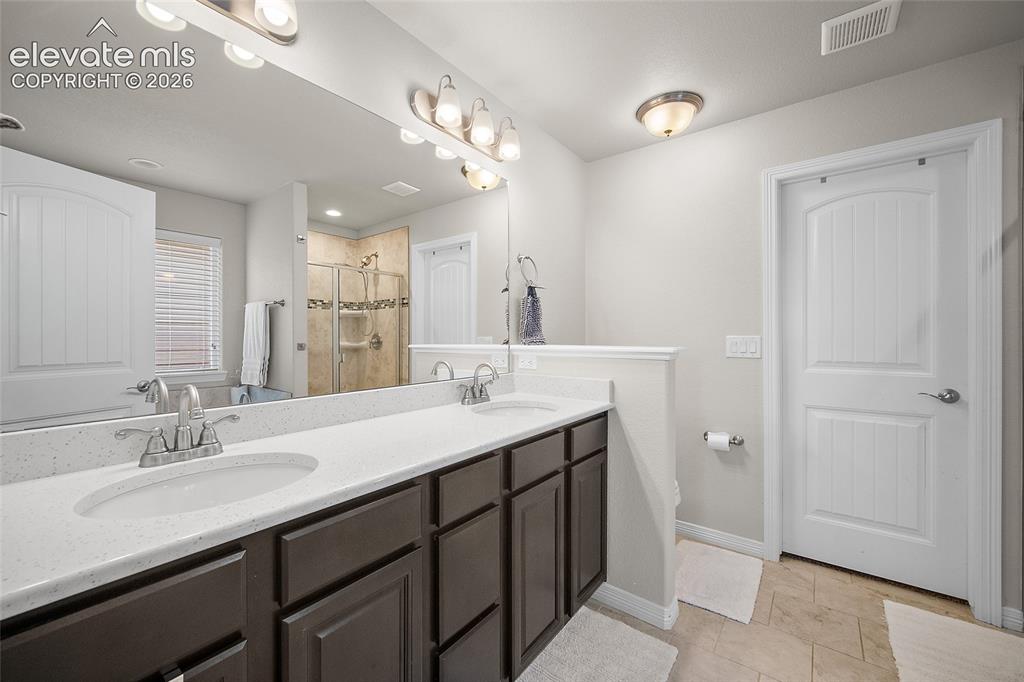 Image 16 of 49: Double vanity featuring white countertops, undermount sinks, and dark wood-