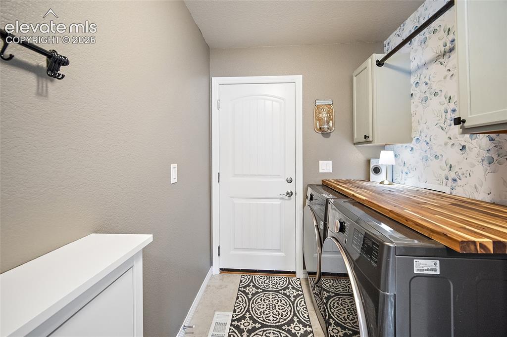 Image 18 of 49: Dedicated laundry space featuring a butcher block countertop, light gray ca